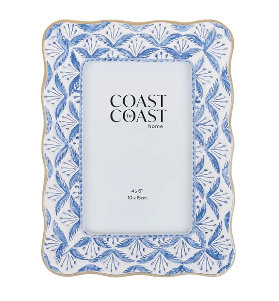A rectangular photo frame with a rounded, scalloped outer edge. The frame is white with a repeating fan-like pattern in various shades of blue. The inner edge of the frame is a thin, rounded, light-brown colour.