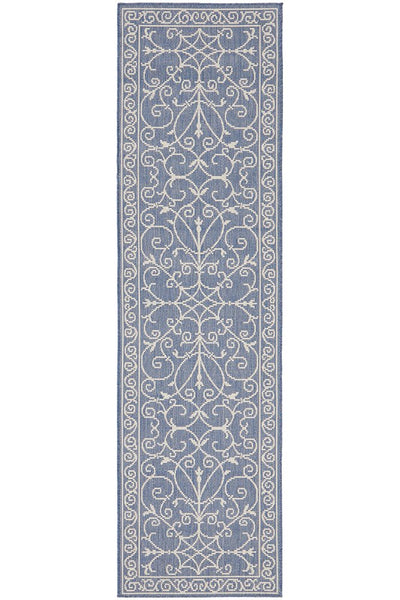 Blue and ivory outdoor runner rug with elegant scroll detailing, styled in a coastal Hamptons-inspired space for indoor or outdoor use.