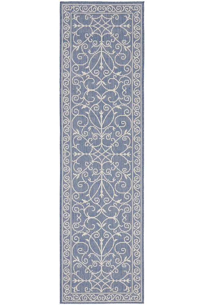 Blue and ivory outdoor runner rug with elegant scroll detailing, styled in a coastal Hamptons-inspired space for indoor or outdoor use.