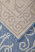 Blue and ivory flatweave outdoor rug featuring an elegant scroll pattern. Showing underside of rug.
