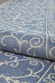 Blue and ivory flatweave outdoor rug featuring an elegant scroll pattern.