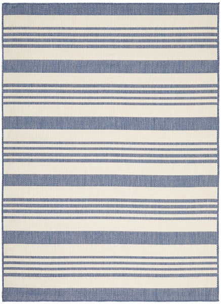 Blue and ivory striped flatweave outdoor rug styled in a coastal setting with rattan furniture, ideal for Hamptons or Malibu-inspired décor.
