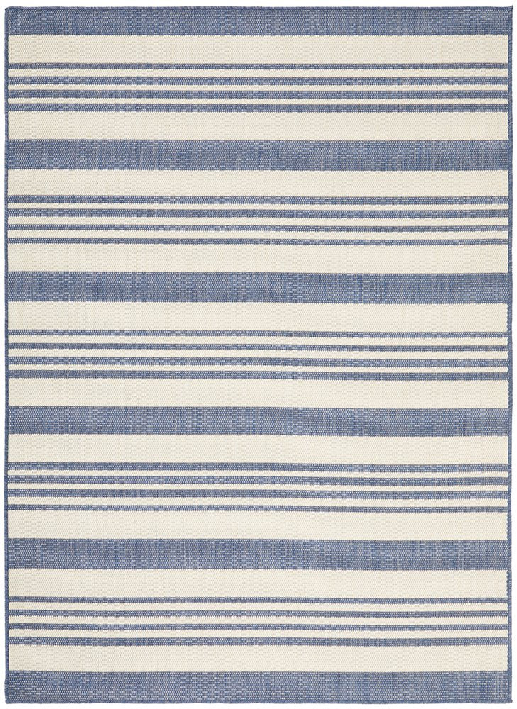 Blue and ivory striped flatweave outdoor rug styled in a coastal setting with rattan furniture, ideal for Hamptons or Malibu-inspired décor.