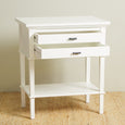 A tall, rectangular bedside table painted in a crisp white finish. It features two drawers stacked on top of an open lower shelf. The drawers have thin, streamlined black metallic handles, and the table legs are straight.
