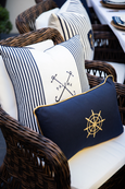 Nautical ships wheel lumbar cushion styled on a wicker outdoor chair with striped coastal cushions.