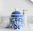 Blue and white ceramic lidded jar with hand-painted scroll design styled on a bathroom countertop.