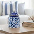 Blue and white ceramic lidded jar with hand-painted scroll design styled on a coffee table in living room.