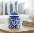 Blue and white ceramic lidded jar with hand-painted scroll design styled on a bathroom countertop.