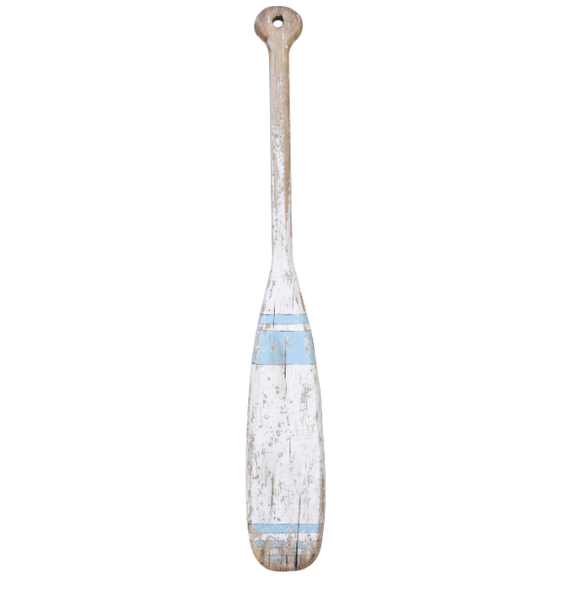 A long, rustic wooden oar with a handle at the top. The wood is a distressed white with a slightly worn finish, and the blade features two faded, horizontal blue stripes. The oar has a rough, weathered appearance.