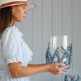 Woman holding a glass vase with blue coral-like decorations against a gray wooden panel background