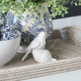 Decorative white birds and a large white acorn on a surface with a blurred background
