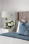 Palm Springs vintage blue velvet cushion styled on a bed with white embroidered detailing in a Hamptons bedroom setting