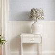 Portico off-white bedside table styled in a coastal bedroom with ceramic lamp and soft blue wall