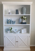 A bookcase styled with hamptons style items.