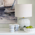 blue ceramic lamp styled on white console with coastal decor