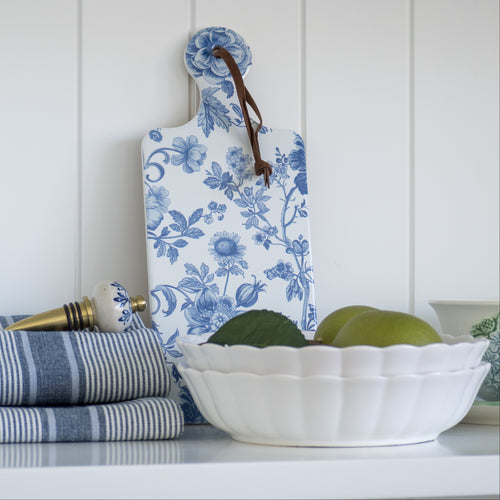 Floral-patterned cutting board on a shelf with kitchen items