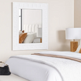 White Rhodes geometric wall mirror styled above a bed in a soft neutral bedroom