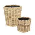 Set of two natural round rattan baskets with black inner pots for indoor plants.