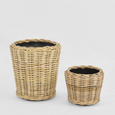 Set of two natural round rattan baskets with black inner pots for indoor plants.