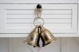Rustic twin metal bells with rope hanger in warm antiqued copper tone.