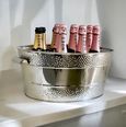 Polished stainless steel oval champagne bucket with dotted double-border design, filled with champagne bottles, perfect for entertaining.