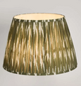 Green pleated lamp shade glowing with warm light ikat pattern