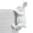 A white ceramic rabbit figurine climbing the side of a matching white ribbed planter pot, shown against a plain white background.
