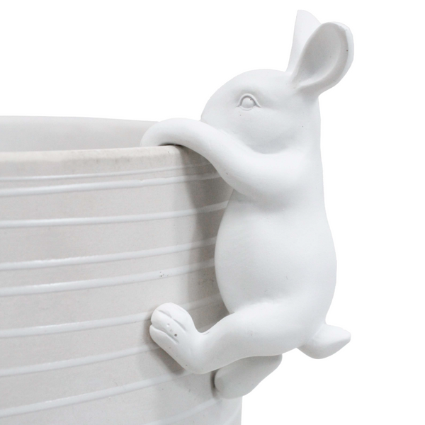 A white ceramic rabbit figurine climbing the side of a matching white ribbed planter pot, shown against a plain white background.