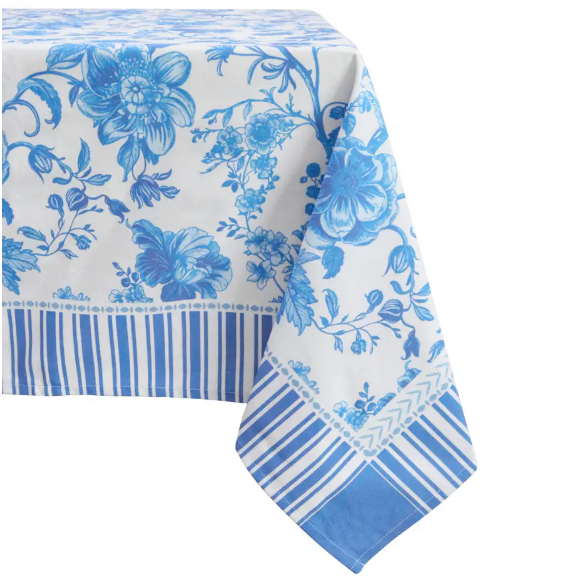 Blue and white floral cotton tablecloth with striped border draped over a dining table