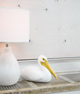 White seated pelican ornament styled beside a ceramic table lamp in a coastal Hamptons interior