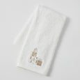 Set of three white cotton Christmas hand towels with champagne-gold embroidered motifs including presents, snow globe, and ‘JOY’ design.