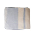 Pale blue and ecru striped linen tablecloth with softly frayed edges styled on a Hamptons-style dining table