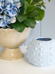 Close-up of a cream crackle-glaze ceramic urn with blue hydrangea arrangement, styled next to a soft blue textured ceramic vase in a coastal Hamptons setting.