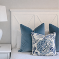 white ceramic table lamp on bedside table with blue velvet cushions and floral cushion, Hamptons style bedroom decor with coastal blue and white styling