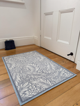 Blue-grey botanical non-slip door mat, 60x90cm, with detailed leaf pattern on timber floor in hallway.
