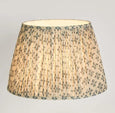 Large blue pleated lamp shade illuminated with warm ambient light