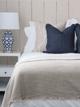 Blue and white Winton jar shaped table lamp with white shade styled beside layered cushions on a neutral upholstered bed