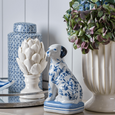 Aarna Ceramic Jar with Lid displayed beside hydrangeas, decorative sculptures and blue and white accents, creating an elegant coastal styling vignette.