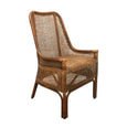 A natural brown rattan dining chair with a high, slightly curved backrest and armrests. The back and seat are both made from tightly woven rattan, and the chair has a classic, elegant silhouette.