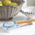 Alice Silicon Spatulas with blue floral pattern displayed on a white tray beside a wicker fruit basket and decorative serving bowls.