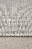 Edge detail of Arden Dove woven rug showing thick hand-stitched border