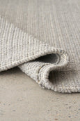 Folded corner of Arden Dove rug highlighting thickness and flexible woven construction