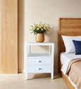 Elegant Arden White Side Table beside a bed featuring dovetailed drawers and a crisp white finish.