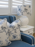 Blue and white floral cushions styled on upholstered armchair with ceramic table lamp, Hamptons style coastal living room decor