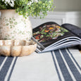 Ascott Navy and White Table Runner styled with greenery, natural ceramic bowl and an open cookbook on a timber table.