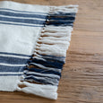 Ascott Table Runner draped over a timber table showing textured navy, white and two-tone tasselled ends.