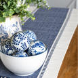 Atlanta Navy Table Runner styled on a timber dining table with blue and white ceramics, decorative balls and greenery.