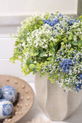 Artificial blue baby breath flowers arranged in vase on coffee table