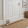 Bailey Bouclé Dog Door Stop styled against a white interior door on a natural woven rug in a coastal-inspired hallway.