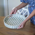 Bari Inlay Tray Blue White small 30cm round decorative tray with striped pattern and cut-out handles being held by a woman to show colour and pattern